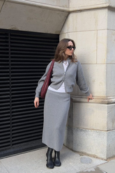 a lady in a white top, a grey cardigan and a grey skirt